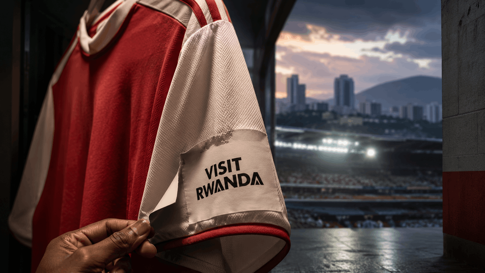 An Arsenal-style football shirt with a peeling “Visit Rwanda” sleeve patch inside a stadium tunnel, symbolising the end of Rwanda’s long-running sponsorship partnership with Arsenal